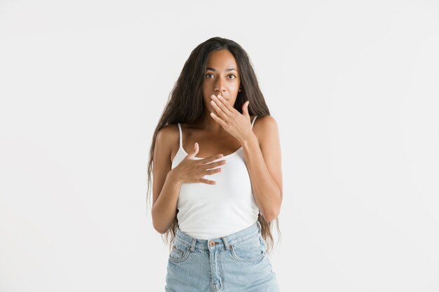 Beau portrait de femme demi-longueur isolé sur fond de studio blanc. Jeune femme afro-américaine émotionnelle aux cheveux longs. Expression faciale, concept d'émotions humaines. Étonné, excité.