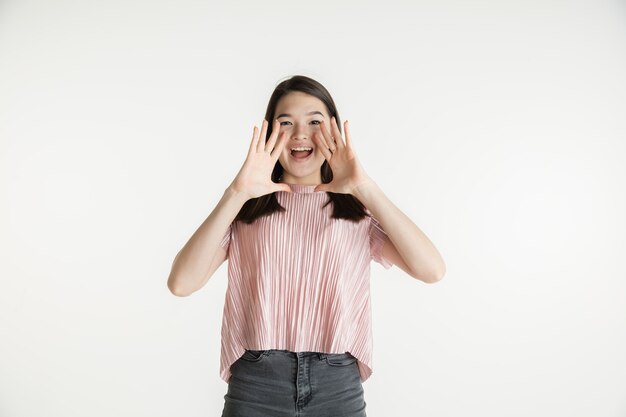 Beau portrait de femme demi-longueur isolé sur fond de studio blanc. Jeune femme émotionnelle dans des vêtements décontractés. Émotions humaines, concept d'expression faciale. Étonné, interrogé, appelant à des ventes.