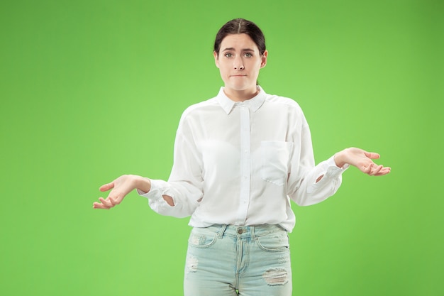 Beau portrait de femme demi-longueur isolé sur un mur vert à la mode. Jeune femme émotionnelle surprise, frustrée et déconcertée. Émotions humaines, concept d'expression faciale.