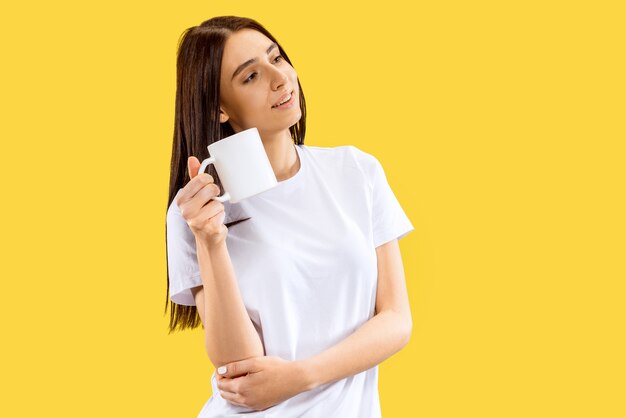 Beau portrait de femme demi-longueur isolé sur studio jaune