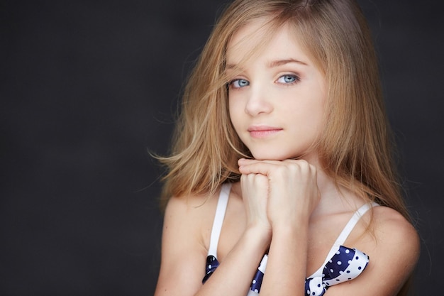 Beau portrait de jeune fille aux yeux bleus. Isolé sur fond gris foncé