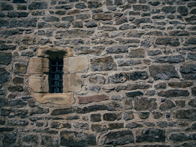 Photo gratuite beau tir d'une ancienne structure en brique de pierre avec une petite fenêtre bloquée