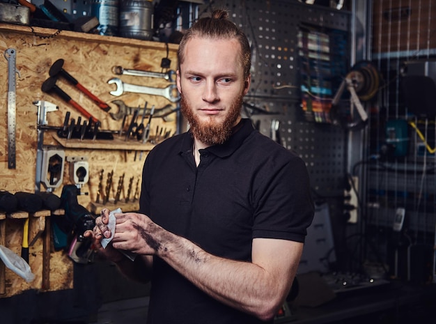 Un beau travailleur rousse élégant, nettoyant ses mains sales après avoir réparé le travail dans un atelier.