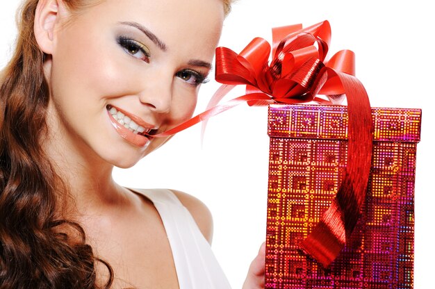 Photo gratuite beau visage de femme souriante avec une boîte rouge mordre légèrement le ruban et le dessiner par les dents