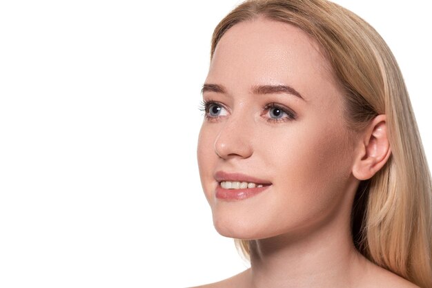 Beau visage de jeune femme blonde avec une peau propre et fraîche et un maquillage naturel sur fond blanc. Modèle sans maquillage. Nu