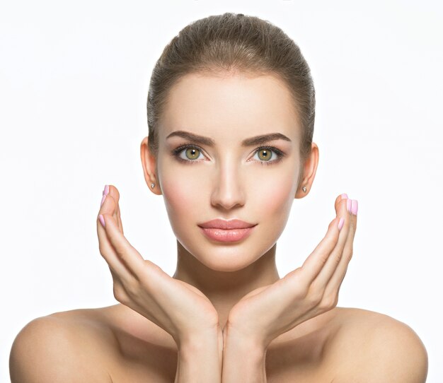 Beau visage de jeune femme caucasienne avec une peau de santé parfaite - isolé sur blanc. Concept de soins de la peau. Le modèle féminin touche le visage.