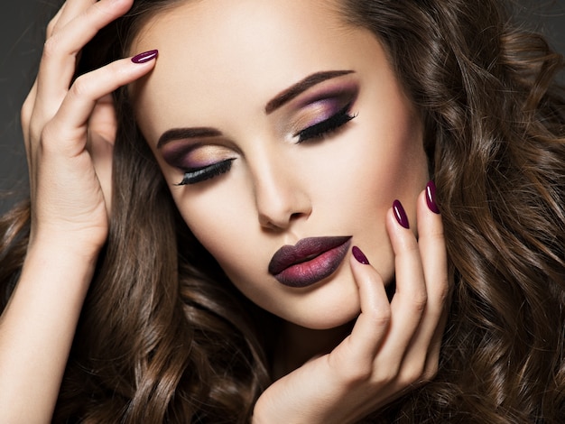 Beau visage de jeune femme avec du maquillage marron. Portrait de fille magnifique avec des lèvres vineuses