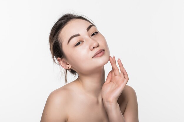 Beau visage d'une jeune femme à la peau douce et propre isolée sur mur blanc. Concept de soins de la peau et du corps.