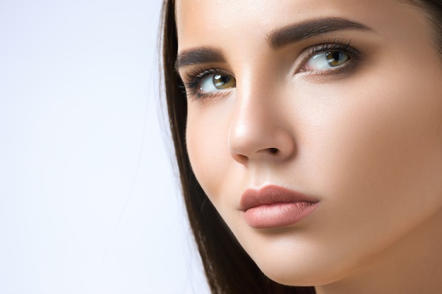 Beau visage de jeune femme avec une peau propre et fraîche bouchent isolé sur blanc.