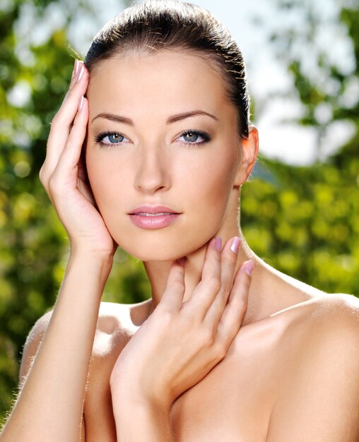 Beau visage sexy d'une jeune femme avec une peau fraîche et saine. Femme posant sur la nature. Modèle caressant son corps.