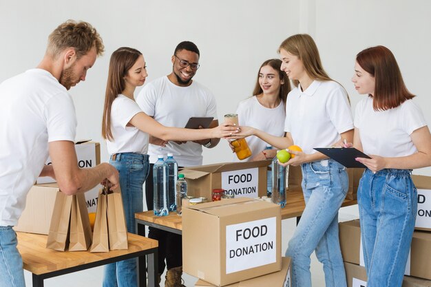 Beaucoup de bénévoles joyeux préparant des boîtes avec des dons de nourriture