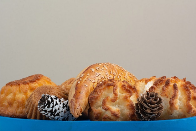 Photo gratuite beaucoup de délicieux biscuits frais avec de petites pommes de pin sur une assiette bleue.