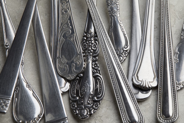 Beaucoup de fourchettes et cuillères en argent avec des motifs anciens sur une surface blanche