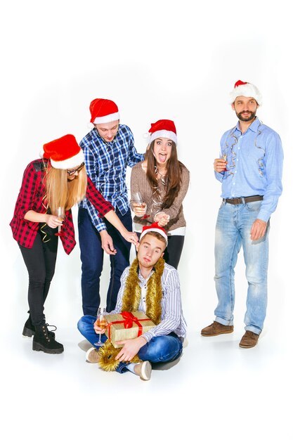 Beaucoup de jeunes femmes et hommes buvant à la fête de Noël sur fond de studio blanc