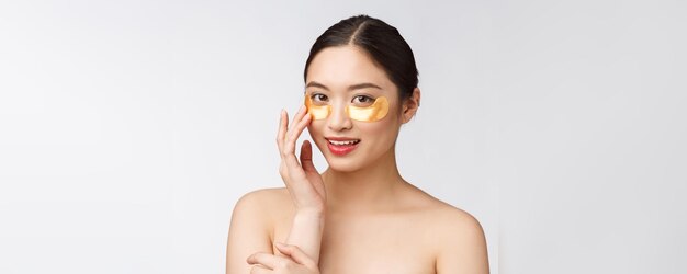 Beauté asiatique adolescent femme soin de sa peau avec des masques pour les yeux d'or sous les yeux