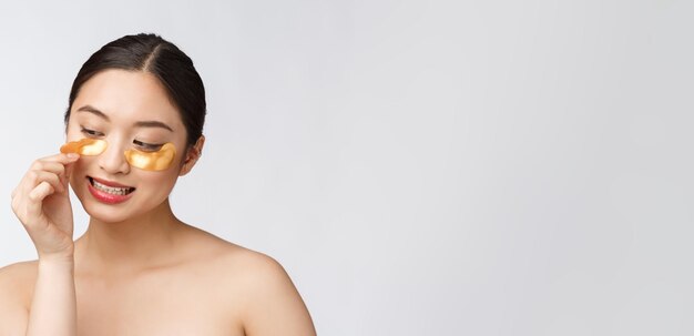 Beauté asiatique adolescent femme soin de sa peau avec des masques pour les yeux d'or sous les yeux