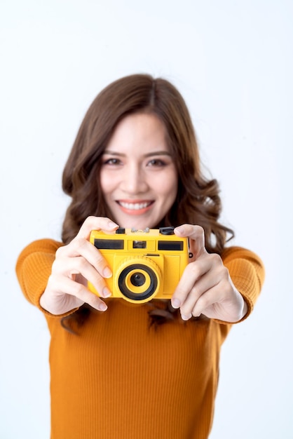 Beauté asiatique femme voyageur main tenir appareil photo jaune rétro avec sourire heureux fond blanc