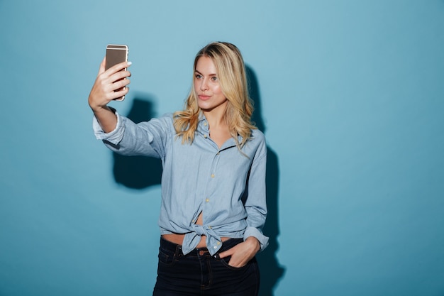 Beauté femme blonde en chemise faisant selfie sur smartphone