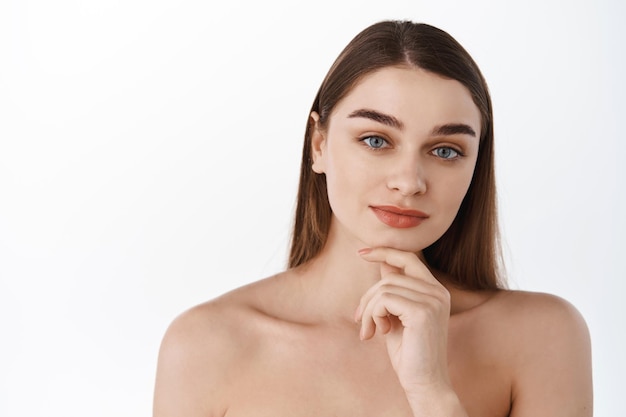 Beauté femme concept de peau saine maquillage naturel beau modèle fille visage mains touchant avec des ongles de manucure. Concept de beauté spa et soins de la peau. Jeune femme regarde pensif à la caméra