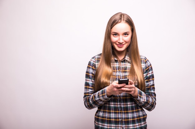 Beauté femme utilisant et lisant un téléphone intelligent isolé sur un mur blanc