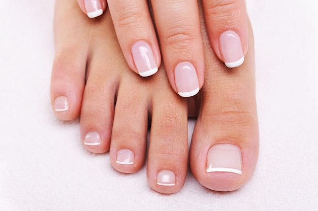 Beauté ongles concept d'une main féminine et pieds avec belle manucure française et pédicure