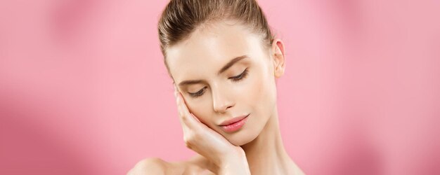 Beauté de la peau Concept Belle jeune femme caucasienne avec une peau propre et fraîche détourner le regard avec fond de studio rose Fille beauté soins du visage Traitement du visage Cosmétologie beauté et spa