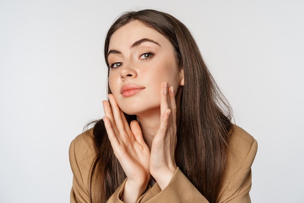 Beauté et soins de la peau portrait en gros plan d'une belle femme regardant dans un miroir et touchant son g clair...