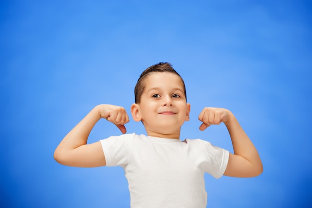 Beauté souriant sport enfant garçon montrant ses biceps