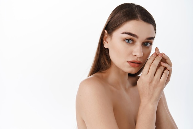 Beauté Spa Femme avec une peau parfaite Portrait Belle Brunette Spa Fille debout près de l'espace de copie vide Proposer un produit Gestes pour la publicité Fond blanc