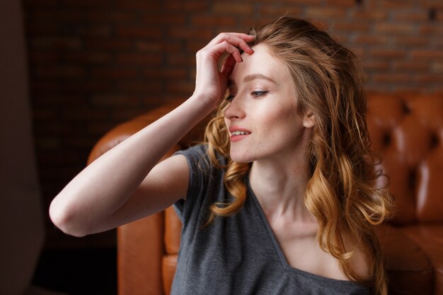 Beauutiful jeune femme avec fond de mur de briques onloft cheveux roux