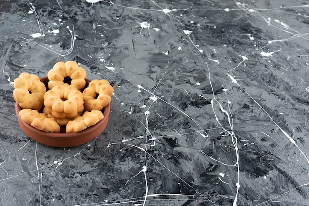 Beaux biscuits sucrés pour le thé dans un bol en argile sur un fond de marbre.