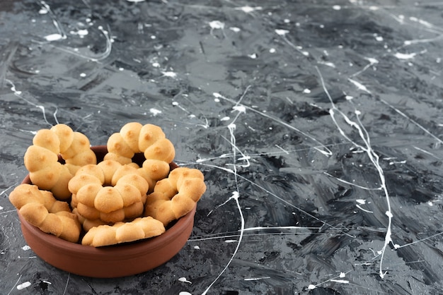 Photo gratuite beaux biscuits sucrés pour le thé dans un bol en argile sur une surface en marbre