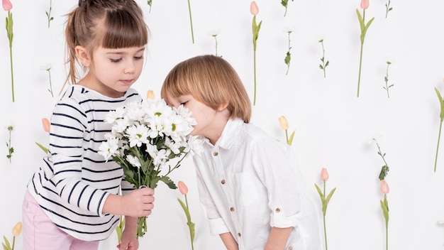 Beaux enfants regardant bouquet de fleurs