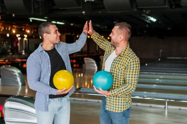 Beaux hommes tenant des boules de bowling colorés