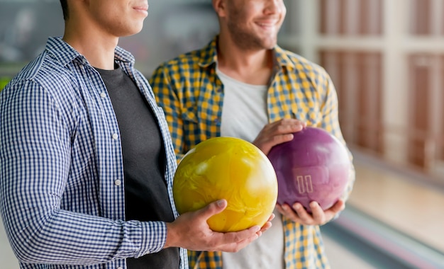 Beaux hommes tenant des boules de bowling colorés