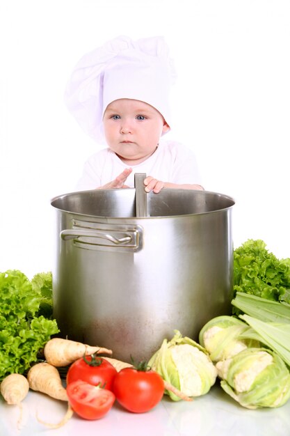 Bébé avec chapeau chef entouré de légumes
