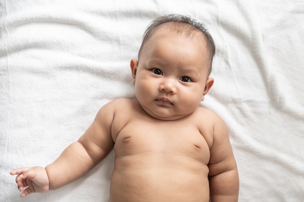 Bébé couché face vers le haut sur un lit blanc