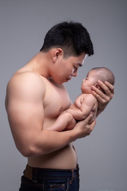 Le bébé dort entre les mains d'un père fort.