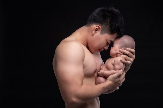 Le bébé dort entre les mains d'un père fort.