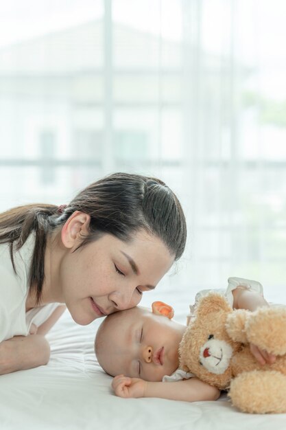 Bébé dort avec un ours en peluche et sa mère s'occupe d'eux