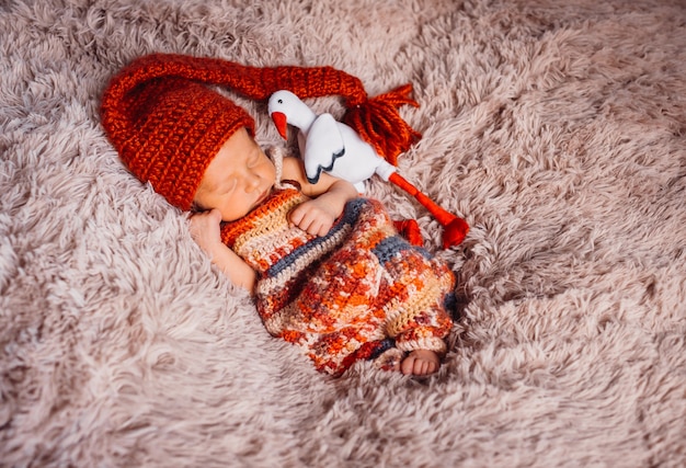 Photo gratuite bébé enveloppé dans une écharpe rouge dort sur une couverture moelleux