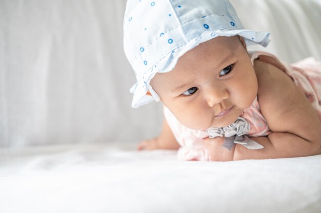 Le bébé est allongé face contre terre sur le lit.