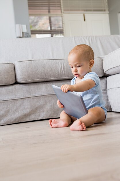 Bébé garçon jouant avec tablette numérique dans le salon