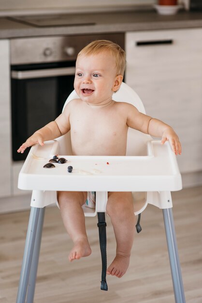 Bébé heureux en chaise haute en choisissant quels fruits manger