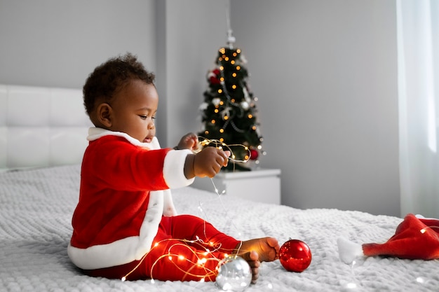 Photo gratuite bébé jouant avec des lumières de noël vue de côté