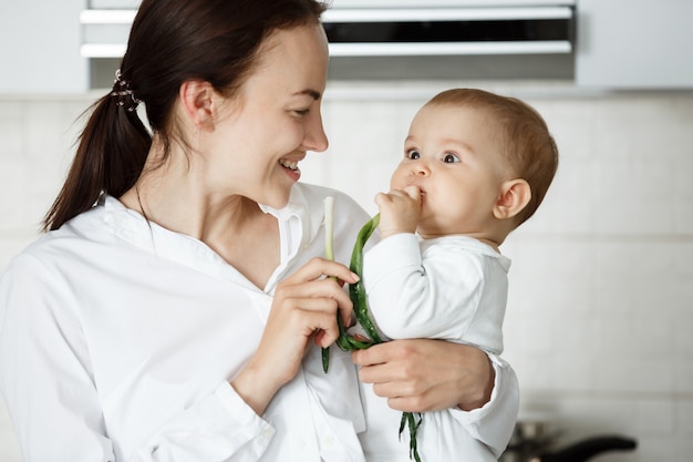 Bébé mignon et sa mère mangeant l'oignon vert