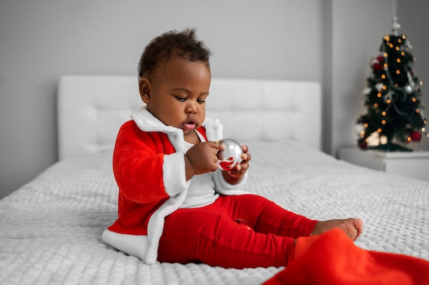 Photo gratuite bébé plein coup assis dans son lit