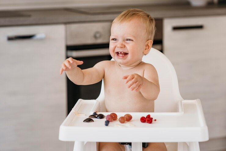 Photo gratuit bébé smiley en chaise haute en choisissant quels fruits manger