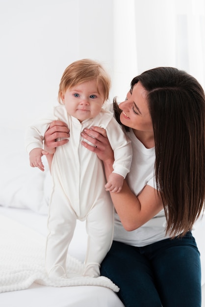 Bébé souriant tenu par la mère et posant