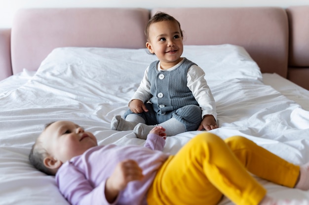 Photo gratuite bébés mignons jouant les uns avec les autres sur le lit et souriant